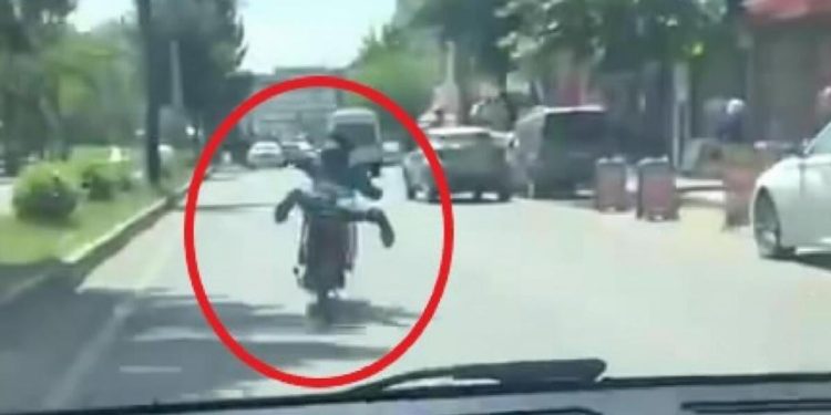 Motosikleti akan trafikte, üzerine yüzüstü yatarak kullandı